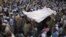 Residents carry the draped body of a suicide bomb victim to his grave in Pabbi, east of Peshawar, in July.