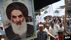 Shi'a carry a poster of Grand Ayatollah Ali al-Sistani as they rally outside the Al-Kholani Mosque in central Baghdad.