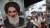 Shi'a carry a poster of Grand Ayatollah Ali al-Sistani as they rally outside the Al-Kholani Mosque in central Baghdad.