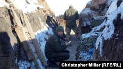 A Ukrainian soldier checks his social-media accounts on his phone while another prepares borsch in a freshly dug trench in Novoluhanske earlier this month.