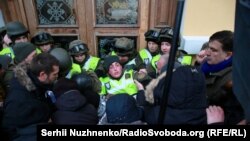 Міхеїл Саакашвілі (праворуч) спостерігає, як мітингувальники, яких він закликав йти до Жовтневого палацу, під час штурму будівлі виривають бійця Нацгвардії зі строю перед центральним входом до будівлі. Київ, 17 грудня 2017 року