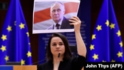 Belarusian opposition leader Svyatlana Tsikhanouskaya delivers a speech as she holds a picture of politician and political prisoner Mikalay Statkevich while receiving the Sakharov human rights prize at the European Parliament in Brussels on December 16.