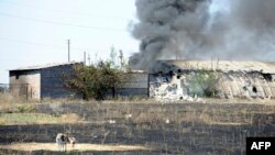 Smoke billows over a damaged building after shelling on the outskirts of the small Ukrainian border town of Novoazovsk, which Kyiv said on August 28 had been seized by Russian tanks and troops. 