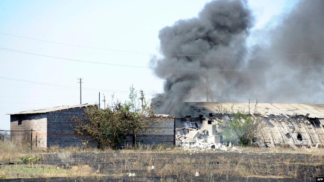Smoke billows over a damaged building after shelling on the outskirts of the small southern Ukrainian city of Novoazovsk on August 27.