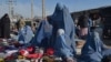 Burqa-clad women sell clothes along a road in Afghanistan (file photo)