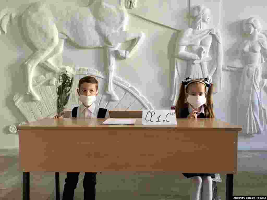 Дівчинка та хлопчик у масках для обличчя в перший день навчання в румунсько-французькій теоретичній середній школі імені Георге Асачі в столиці Молдови Кишиневі 1 вересня