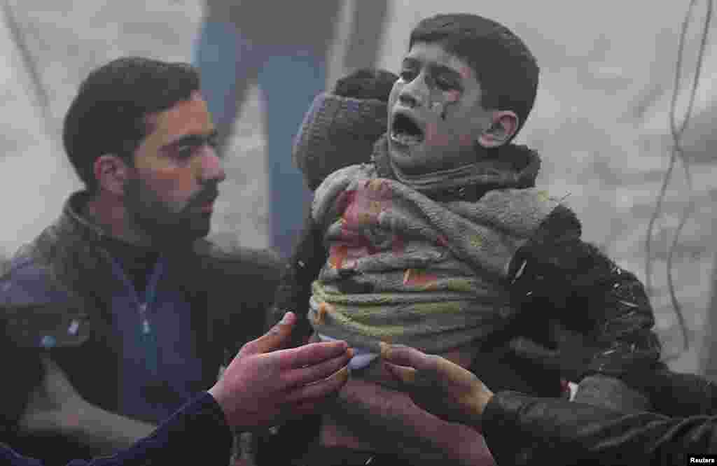 Men help a wounded boy who survived what activists say was an air strike by forces loyal to Syrian President Bashar al-Assad in the Duma neighbourhood of Damascus. (Reuters/Bassam Khabieh)