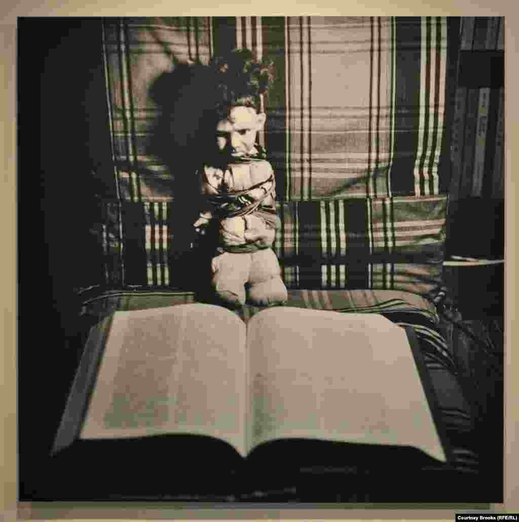 A bound doll sits in front of a book.