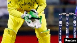 Australia -- Afghan captain Mohammad Nabi plays a sweeper which is caught out by Australia's captain, as wicketkeeper Brad Haddin (L) watches on, during their Cricket World Cup match in Perth, March 4, 2015