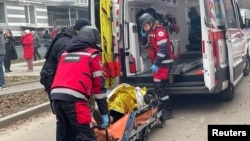 Emergency workers carry an injured resident into an ambulance at the site of an apartment building that was hit by a Russian drone strike in Chernihiv on December 25. 