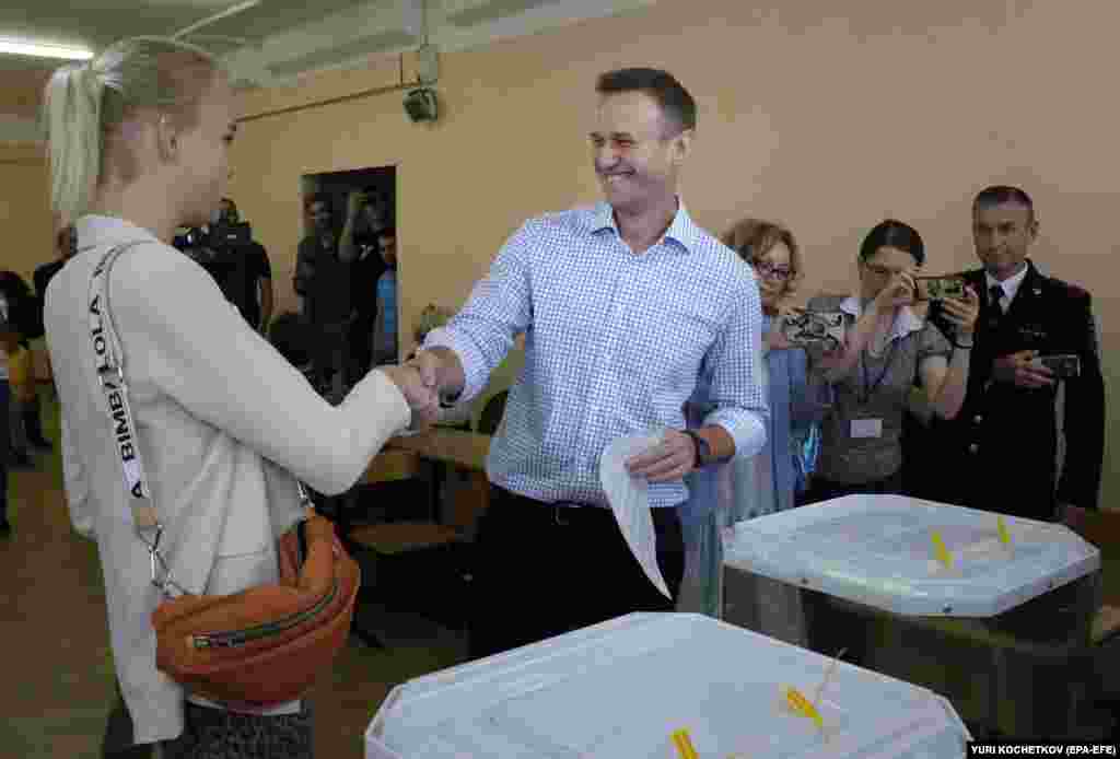 Russian opposition politician Aleksei Navalny shakes hands with his daughter Daria as he votes at a polling station during the Moscow city council elections on September 8.&nbsp;The elections have drawn fierce protests after several opposition candidates allied with Navalny were barred from standing.