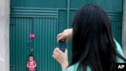 A woman photographs her daughter at a gate of Osama's compound 