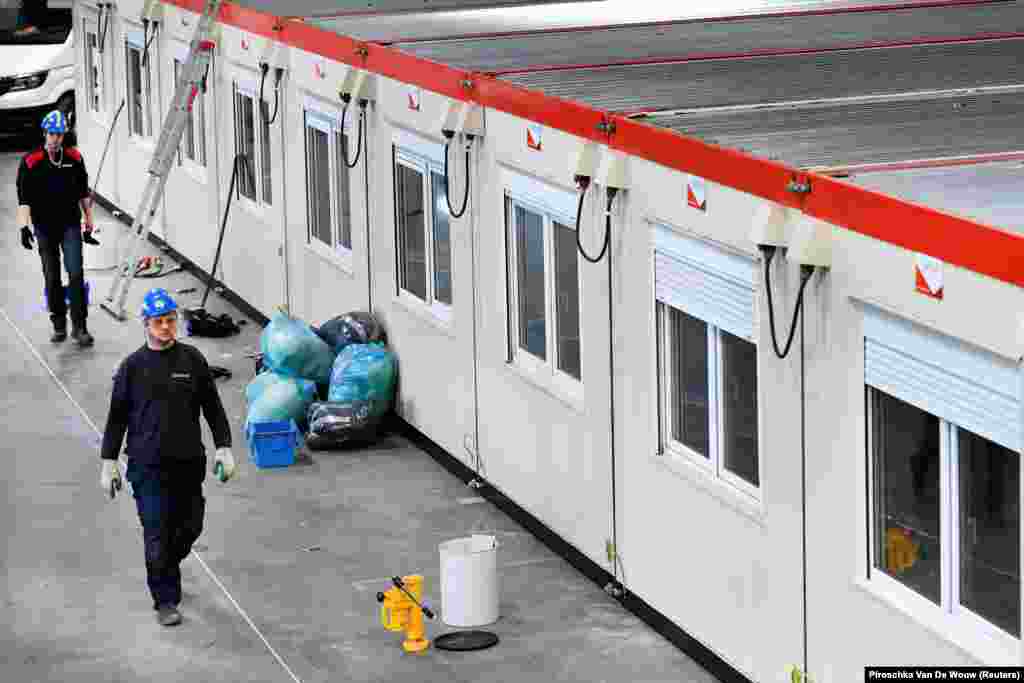 Dutch workers walk inside Rotterdam&#39;s Ahoy concert hall, which was meant to host the Eurovision Song Contest in May. The competition was canceled and the venue was converted into an emergency hospital.