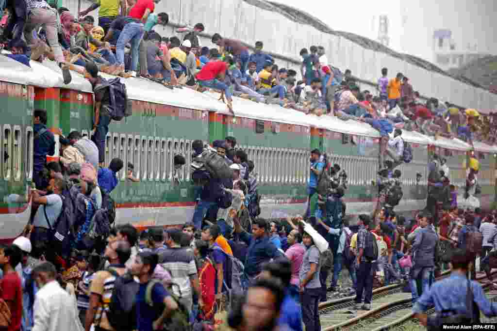 People climb on the roof of an overcrowded train as they travel to their home villages to celebrate Eid al-Adha at the Kamlapur Railway Station in Dhaka, Bangladesh. Eid al-Adha is the holiest of the two Muslims holidays celebrated each year. It marks the yearly Muslim pilgrimage to visit Mecca. (epa-EFE/Monirul Alam)