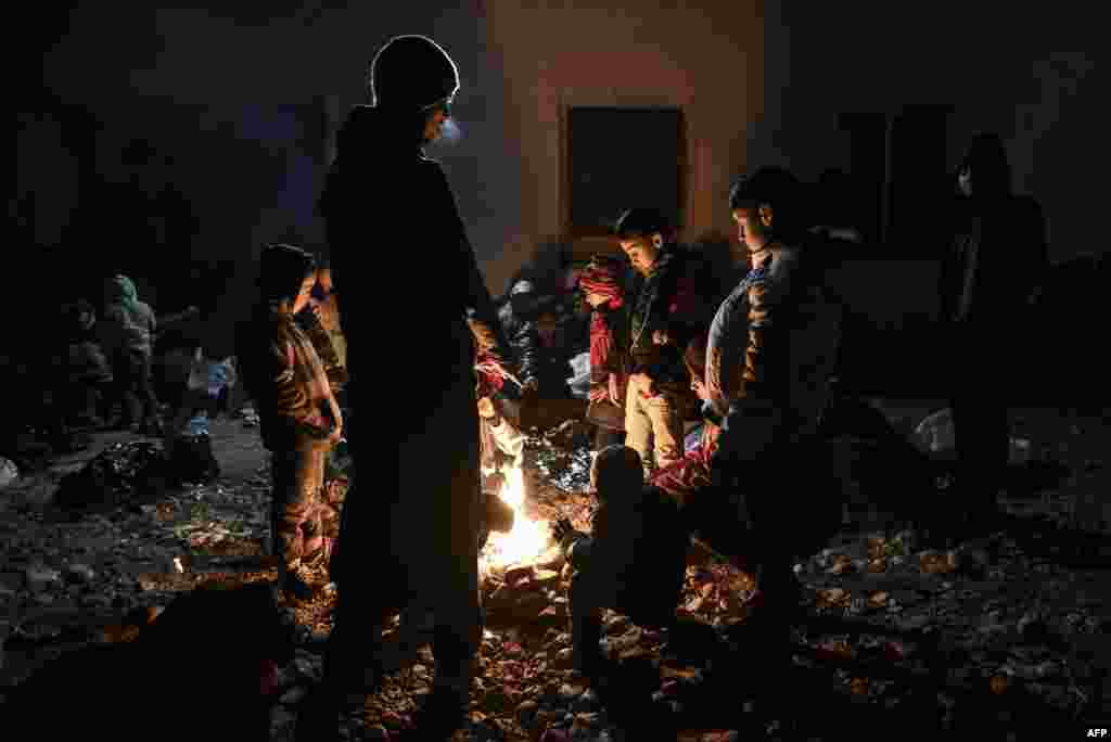 Migrants and refugees warm up around a bonfire as they wait to enter an accommodation camp after crossing the Greek border near Gevgelija in Macedonia on December 6. (AFP/Armend Nimani)