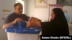 سيدة تضع إستمارة إقتراعها في الصندوق في محطة إنتخابية بمدينة العمارة