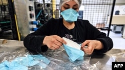 An employee packs respiratory protective face masks on an assembly line in Mably in central France.