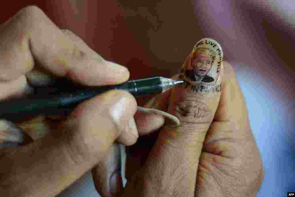 An Indian artist draws a miniature portrait of former South African President Nelson Mandela on his thumbnail as part of his homage in Siliguri. (AFP/Diptendu Dutta)