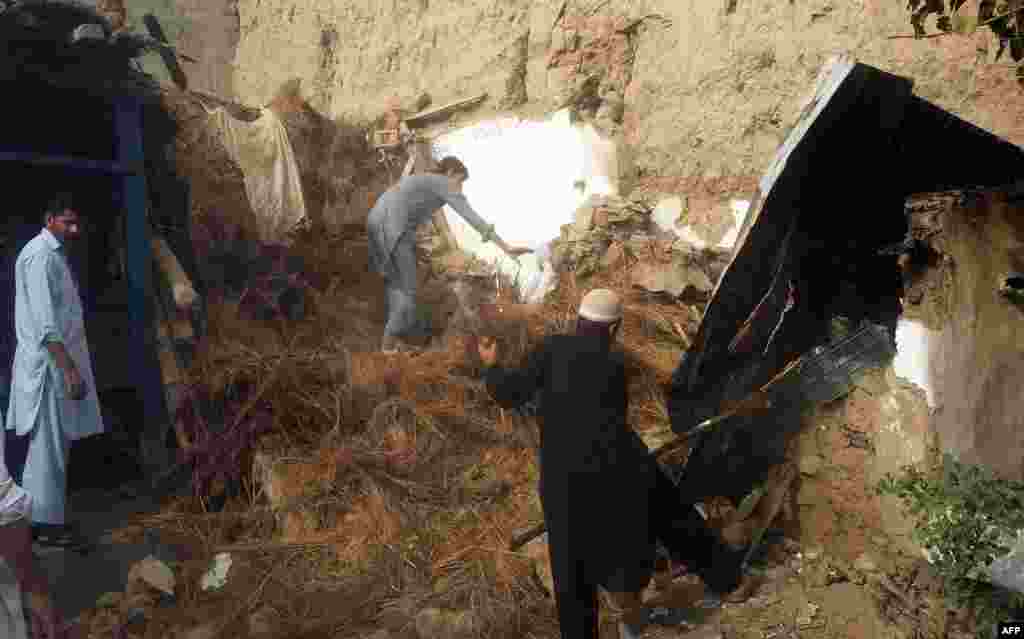 Pakistani residents in Lower Dir search under the rubble of a house for survivors.