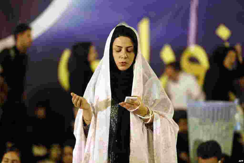 An Iranian woman holds her mobile phone as she prays at the Imam Khomeini grand mosque in the capital, Tehran. (AFP/Atta Kenare)