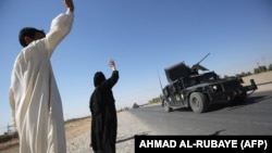 Residents wave to Iraqi forces as they arrive in the first neighborhood on the southern outskirts of Kirkuk on October 16. 