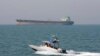 FILE-- In this July 2, 2012 file photo, an Iranian Revolutionary Guard speedboat moves in the Persian Gulf while an oil tanker is seen in background. 