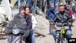 Tehranda motosikletçilər Firdovsi meydanının yaxınlığında dağıdılmış və zədələnmiş binaların yanından keçirlər.