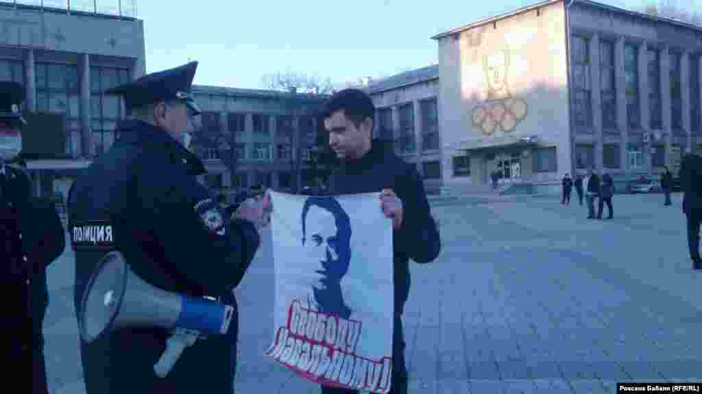 Қиыр Шығыстағы Амурдағы-Комсомольск қаласында өткен шеруге &quot;Навальныйға бостандық&quot; деген плакат ұстап шыққан адаммен сөйлесіп тұрған полицей.