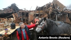Farmer Tomislav Suknaić miluje konja ispred svog oštećenog domaćinstva u selu Majske Poljan nakon zemljotresa u Hrvatskoj, 30. decembra 2020.