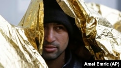 A migrant covers himself with a thermal blanket as he waits in line to get food at a migrant center in Bihac, close to Bosnia's border with Croatia, in November.