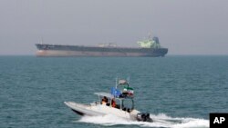 FILE-- In this July 2, 2012 file photo, an Iranian Revolutionary Guard speedboat moves in the Persian Gulf while an oil tanker is seen in background. 