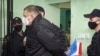 Bloggerul Serghie Țihanovski (centru) în fața cuștii în care va fi ținut în sala de judecată (fotografie de arhivă).
