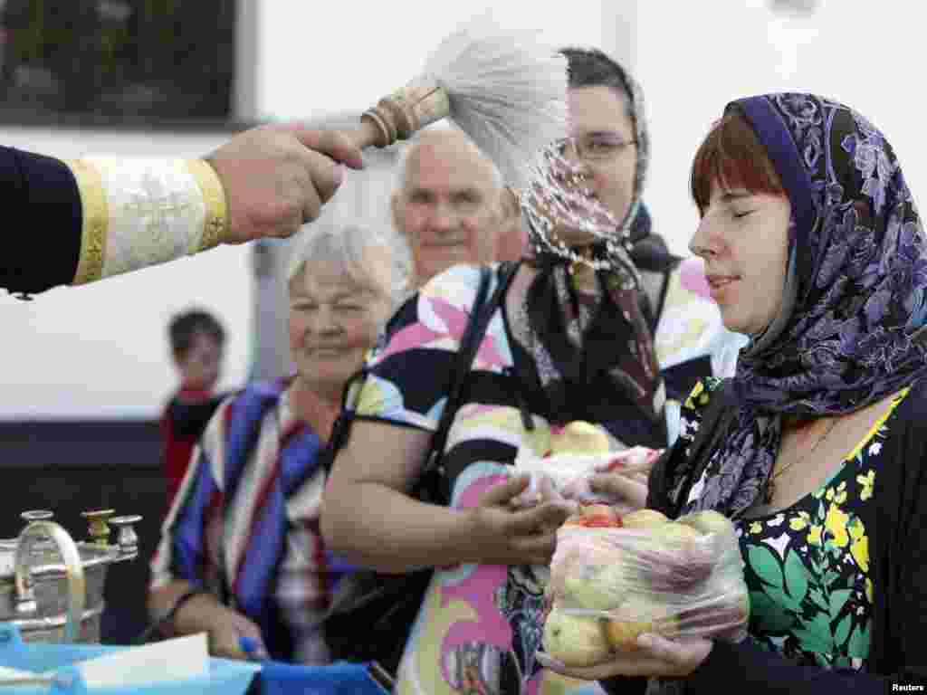 Believers are blessed by an Orthodox priest at a church during the Yablochny Spas, or Apple the Saviour religious holiday in Minsk, Belarus. The holiday, which is also known as the Transfiguration of Jesus Christ, is celebrated by believers who gather ripened fruit, bring it to the church for blessing, and then eat it to celebrate the reappearance of Christ before his three closest followers.Photo by Vasily Fedosenko for Reuters