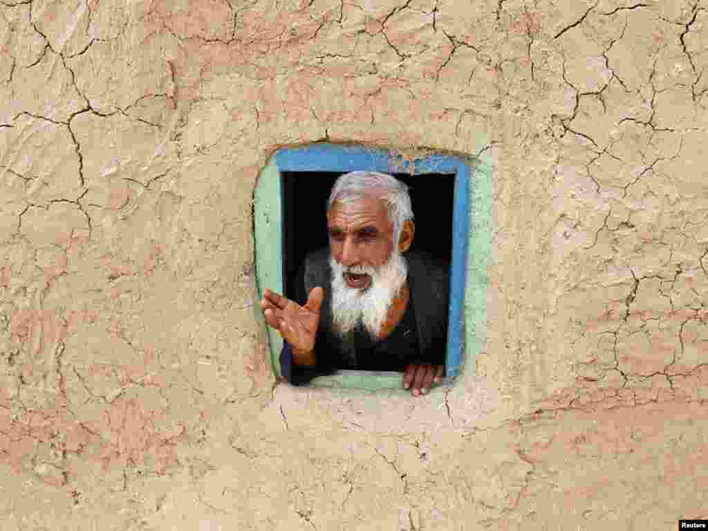 An internally displaced Afghan man talks from a small window at a refugee camp in Kabul on July 28. Photo by Omar Sobhani for Reuters