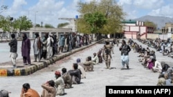  People sit on the ground to maintain social distanciation as they wait to collect free dry rations from the Saylani Welfare Trust during a government-imposed nationwide lockdown in the southwestern city of Quetta on March 31.