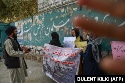 A member of the Taliban speaks with women protesters as another tries to block the view of the camera during a demonstration held outside a school in Kabul.