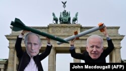 Activiști pentru pace cu măștile președinților Vladimir Putin și Joe Biden, la Berlin