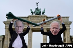 Peace activists wearing masks of Russian President Vladimir Putin (left) and U.S. President Joe Biden pose with mock nuclear missiles in front of Berlin's Brandenburg Gate. (file photo)