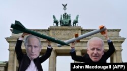 Activiști pentru pace purtând măștile președintelui Federației Ruse, Vladimir Putin (stânga), și a recent alesului președinte al Statelor Unite, Joe Biden, pozează în fața Porții Brandenburg, 29 ianuarie 2021