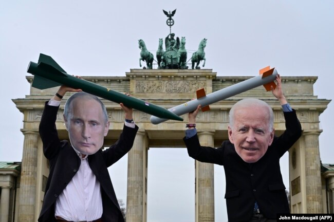 Peace activists wearing masks of Russian President Vladimir Putin (left) and U.S. President Joe Biden pose with mock nuclear missiles in front of Berlin's Brandenburg Gate. (file photo)