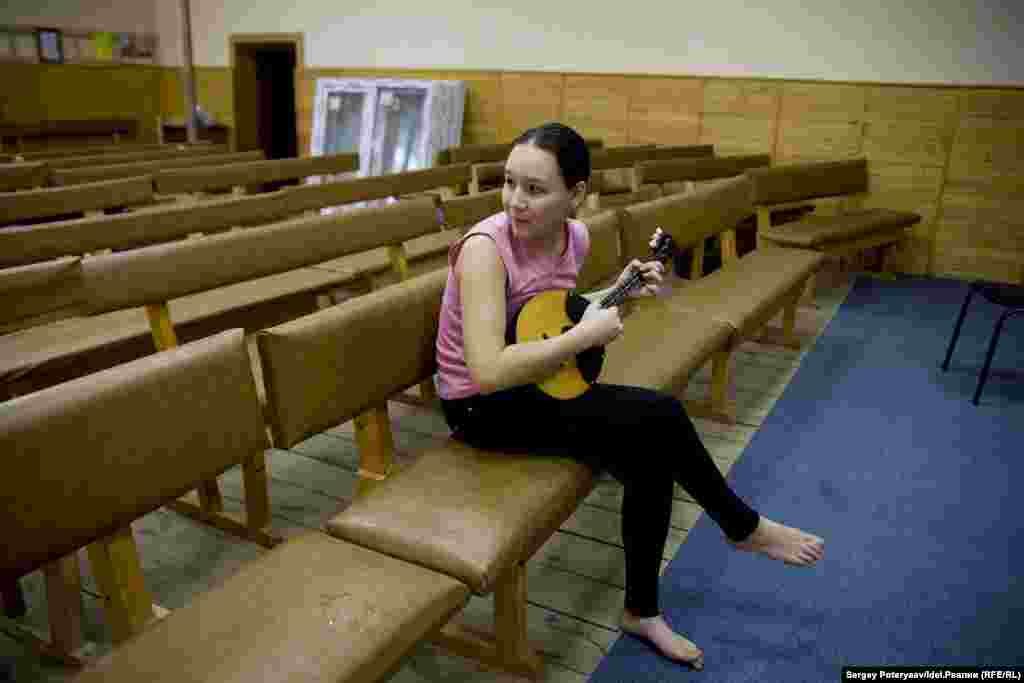 Дочка руководителя церкви репитирует на домре в главном зале для богослужений