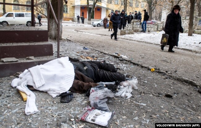 Хора минават покрай тялото на жертва след обстрел в източния украински град Крамоторск, 10 февруари 2015 г.