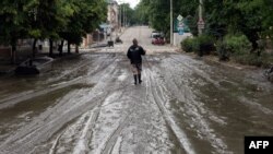 Місцевий житель йде брудною вулицею після затоплення частини Херсона 12 червня 2023 року
