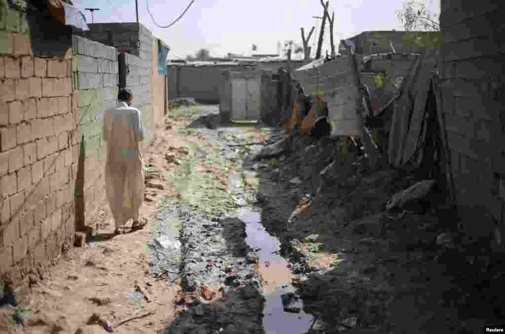 An Iraqi Shi&#39;ite cleric walks through a poor neighborhood in the Al-Fdhiliya district.