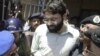 Pakistani police surround handcuffed Omar Sheikh as he comes out of a court in Karachi in 2002.