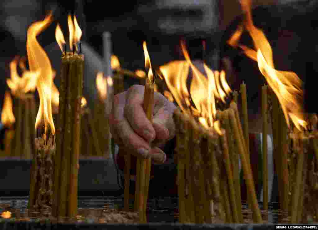 An Orthodox believer lights candles during a Christmas mass outside the central Orthodox Church of Saint Clement in Skopje, North Macedonia, on January 7. (epa-EFE/Georgi Licovski)&nbsp;