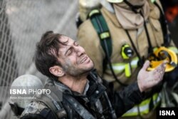 عکسی از خبرگزاری ایسنا که یکی از آتش‌نشان‌ها را ساعتی پس از فروریختن پلاسکو و زیرآوار ماندن هم‌قطارانش نشان می‌دهد