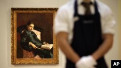 Сотрудник аукциона Sotheby's перед выставленной на торги картиной кисти Ильи Репина "Портрет жены художника". Лондон, 2011 год
