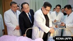 Kim Jong-Un (ortada) Şimali Koreyada xəsarət almış çinli turistə baş çəkir, arxiv fotosu