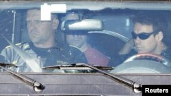 Accused gunman Anders Behring Breivik, partially obscured by a rearview mirror, sits in a police vehicle as he is escorted from Ila prison in Baerum, to be brought to the main police station in Oslo for questioning on July 29